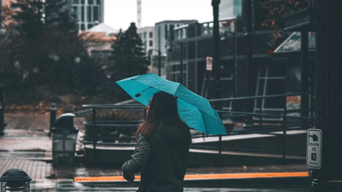 People with umbrellas on a wet Vancouver street in the rainy season, when slower outdoor work and full rent bring many short loans